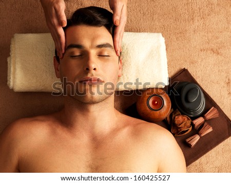 Masseur doing head massage of temples on man in the spa salon.