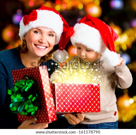 Mother with little child opens the box with gifts on the christmas holiday - indoors