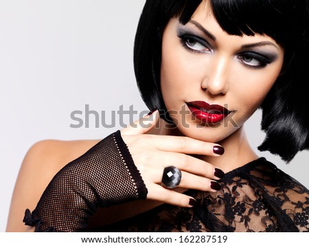 Fashion photo of a beautiful brunette woman with shot hairstyle. Closeup girl\'s face with red lips and nails