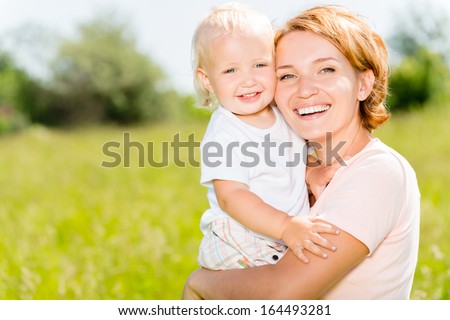 Happy Mother And Toddler Son In The Spring Meadow Outdoor Portrait