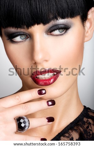 Face Of A Woman With Beautiful Dark Nails And Sexy Red Lips. Fashion Model With Black Shot Hairs At Studio