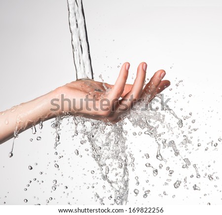 Closeup woman hand under the stream of splashing water - skin care concept