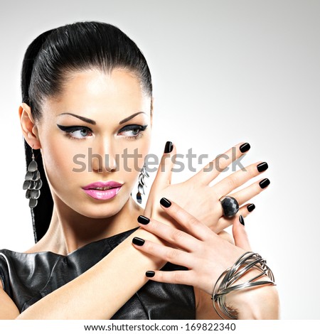 Beautiful fashion sexy woman with black nails at pretty face. Pretty girl model with stylish bijouterie of  silver color.