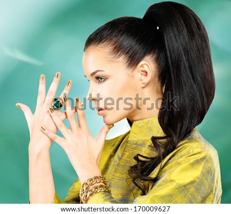 Fashion woman with golden nails and beautiful  emerald ring