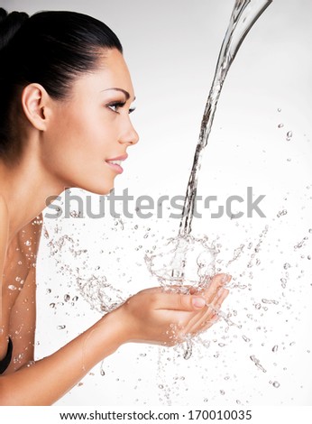 Closeup portrait of a beautiful woman washing her clean face with water