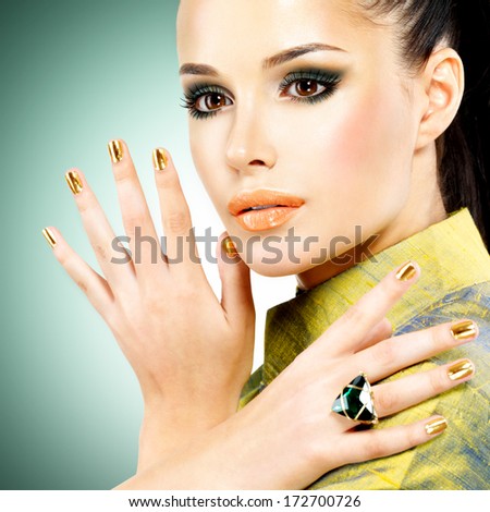 Glamour woman with beautiful golden nails and emerald ring on hands