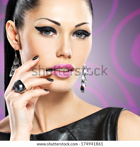 Portrait of a beautiful  fashion woman with black nails and bright makeup.  Pretty sexy face of a glamour girl posing at studio over art color background