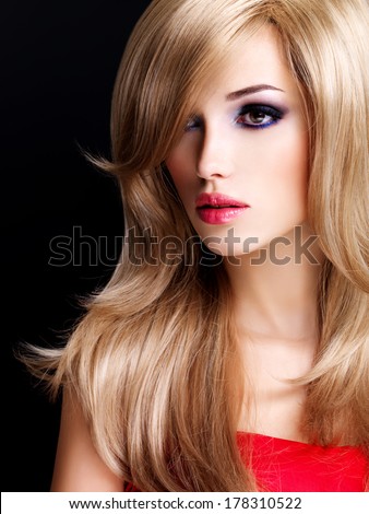 Closeup portrait of a beautiful young woman with long white hairs and red lips. Fashion model posing at studio over black background