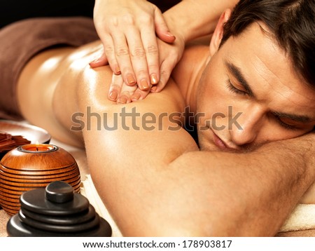 Masseur doing massage on man body in the spa salon. Beauty treatment concept.
