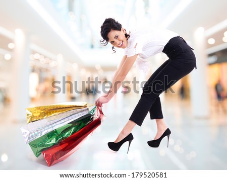 Happy attractive woman drags colorful shopping bags - isolated on white.