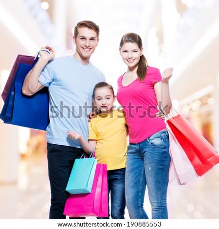 Happy family with shopping bags standing at studio over white background.