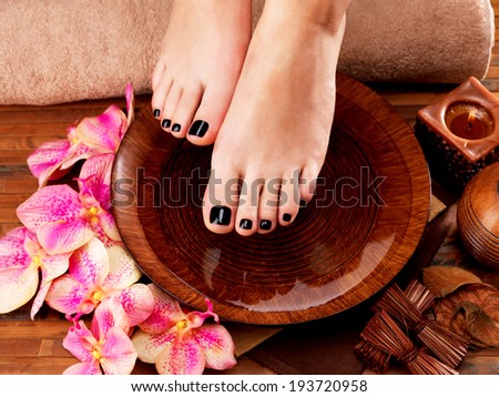 Beautiful women legs with black pedicure after Spa procedures Spa treatment concept Beautiful women legs with black pedicure after Spa procedures Spa treatment concept