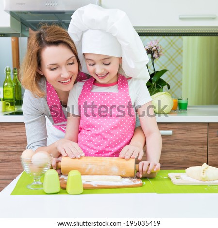 Portrait of happy smiling mother and daughter making pies together at the kitchen.