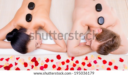 Beautiful couple relaxing in spa salon with hot stones on body. Beauty treatment therapy.