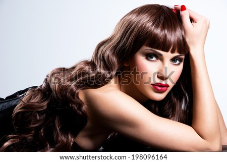 Beautiful sexy woman with red nails and lips posing at studio.