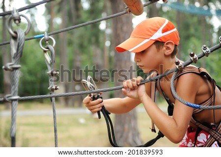 Portrait of young boy engaged climbing at the rope course.