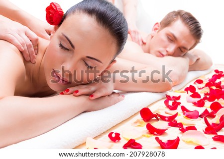 Attractive couple lying in a spa salon enjoying a deep tissue back massage together.