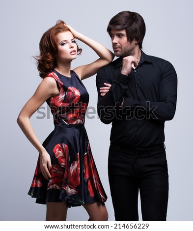 Portrait of luxury young couple in love posing at studio dressed in classic clothes.