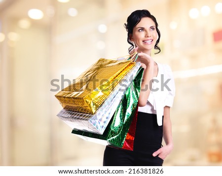 Happy laughing young woman with color bags looking up in the shop.