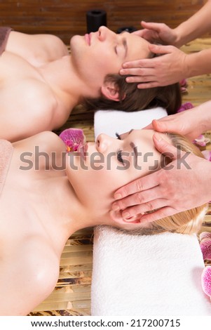 Beautiful couple lying in a spa salon enjoying head massage together.