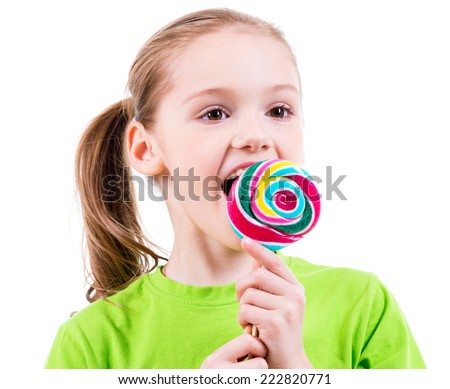 Smiling little girl in green t-shirt eating colored candy - isolated on white.