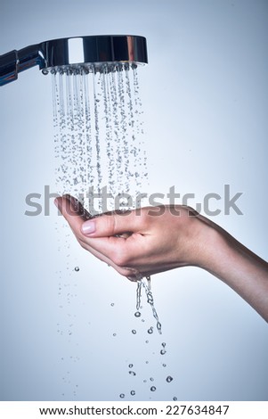 Closeup female hands under the stream of  water from shower - skin care concept