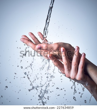 Closeup female hands under the stream of splashing water - skin care concept