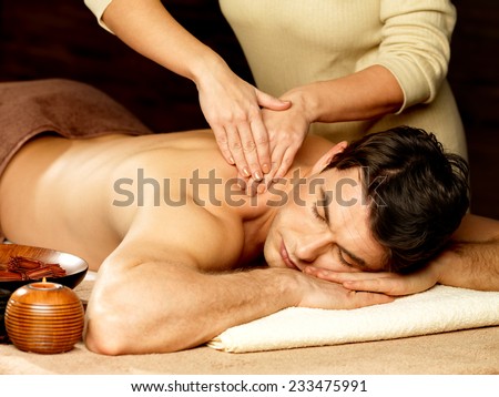 Masseur doing massage on man body in the spa salon. Beauty treatment concept.