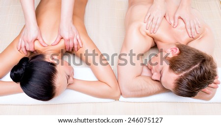 Portrait of beautiful couple lying  in a spa salon enjoying a deep tissue back massage together.