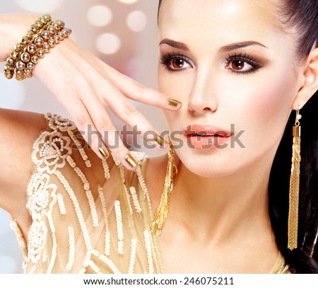 Pretty woman with golden nails and beautiful gold jewelry isolated on white background