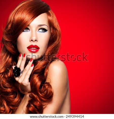 Beautiful sensual woman with long red hairs and red nails on red background