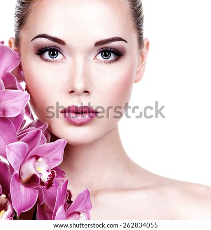 Closeup face of an young beautiful woman with a purple eye makeup and lips. Pretty adult girl with flower near the face.  - isolated on white background