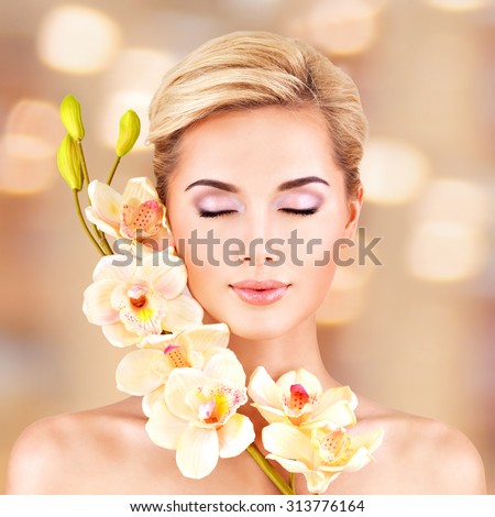 Closeup face of an young woman with health skin and flowers at face. Beauty treatment concept.
