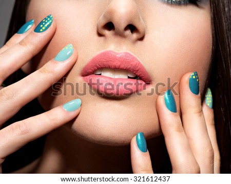 Woman\'s fingers with motton blue color of the nails on the face