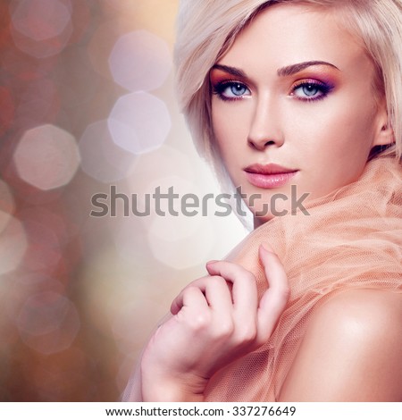 Close-up portrait of sensual young woman in the beige fabric over creative background.