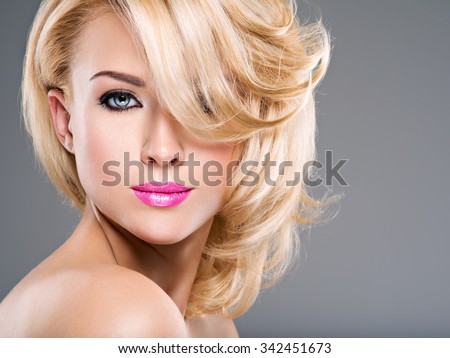 Beautiful woman with long blond curly hair. Portrait of fashion model with bright makeup.