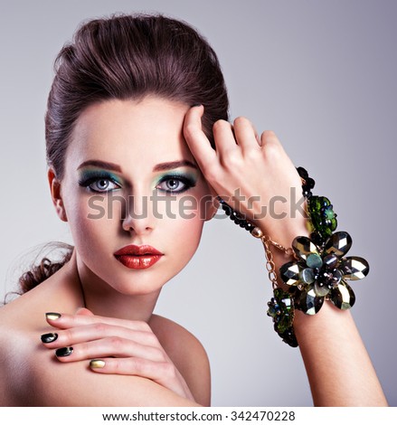 Beautiful woman face with fashion green make-up and jewelry on hand