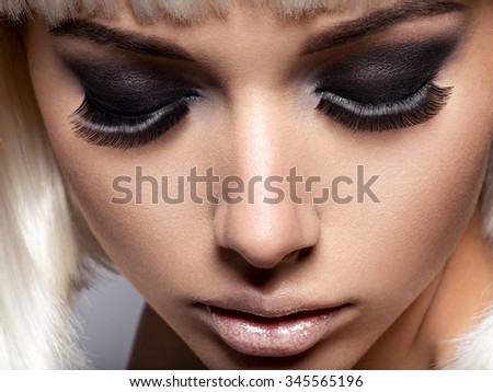 The girl\'s face closeup with long black lashes. fashion makeup