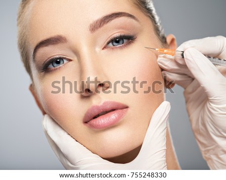 Woman getting cosmetic injection of botox in cheek, closeup. Woman in beauty salon. plastic surgery clinic.