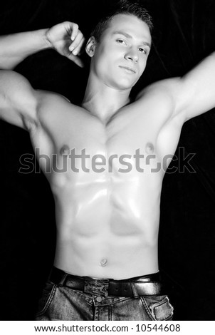 Sexy young guy lying on the black background.