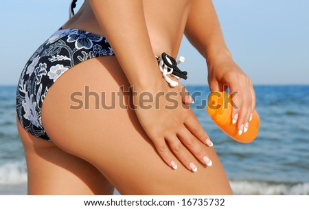 Woman applying suntan lotion on leg