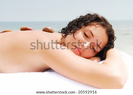 Young woman with row of stones on back having a spa treatment.
