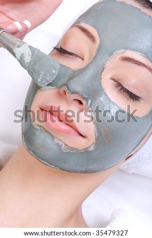 cosmetic procedure with clay on the young female face close-up