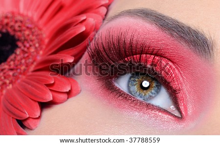 fashion woman eye with red make-up and long false eyelashes -  flower at background