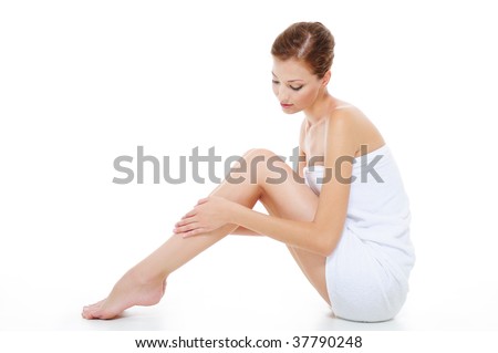 Beautiful young woman in towel sitting on the floor and stroking her beauty legs Beautiful young woman in towel sitting on the floor and stroking her beauty legs