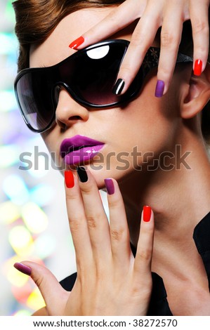 Face of young woman with multicolored manicure and fashion stylish sunglasses - colored background