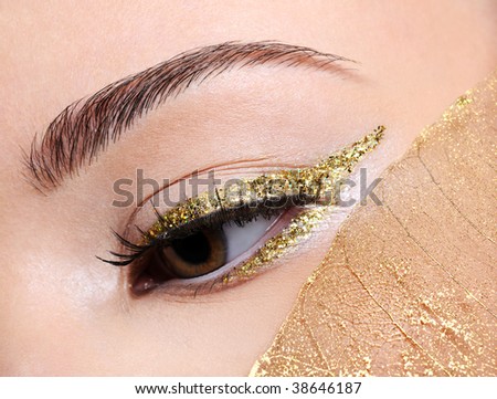 Fashion make-up in golden eyeliner arrow on the female with a yellow leaf