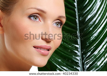 Woman natural healthy clear skin and the big leaf as a background