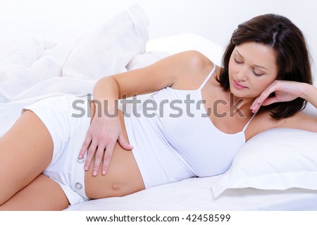 stock photo Pregnant young woman caring of baby by stroking her belly