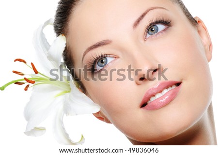 Healthy skin of young beautiful woman face with a flower in her hairs